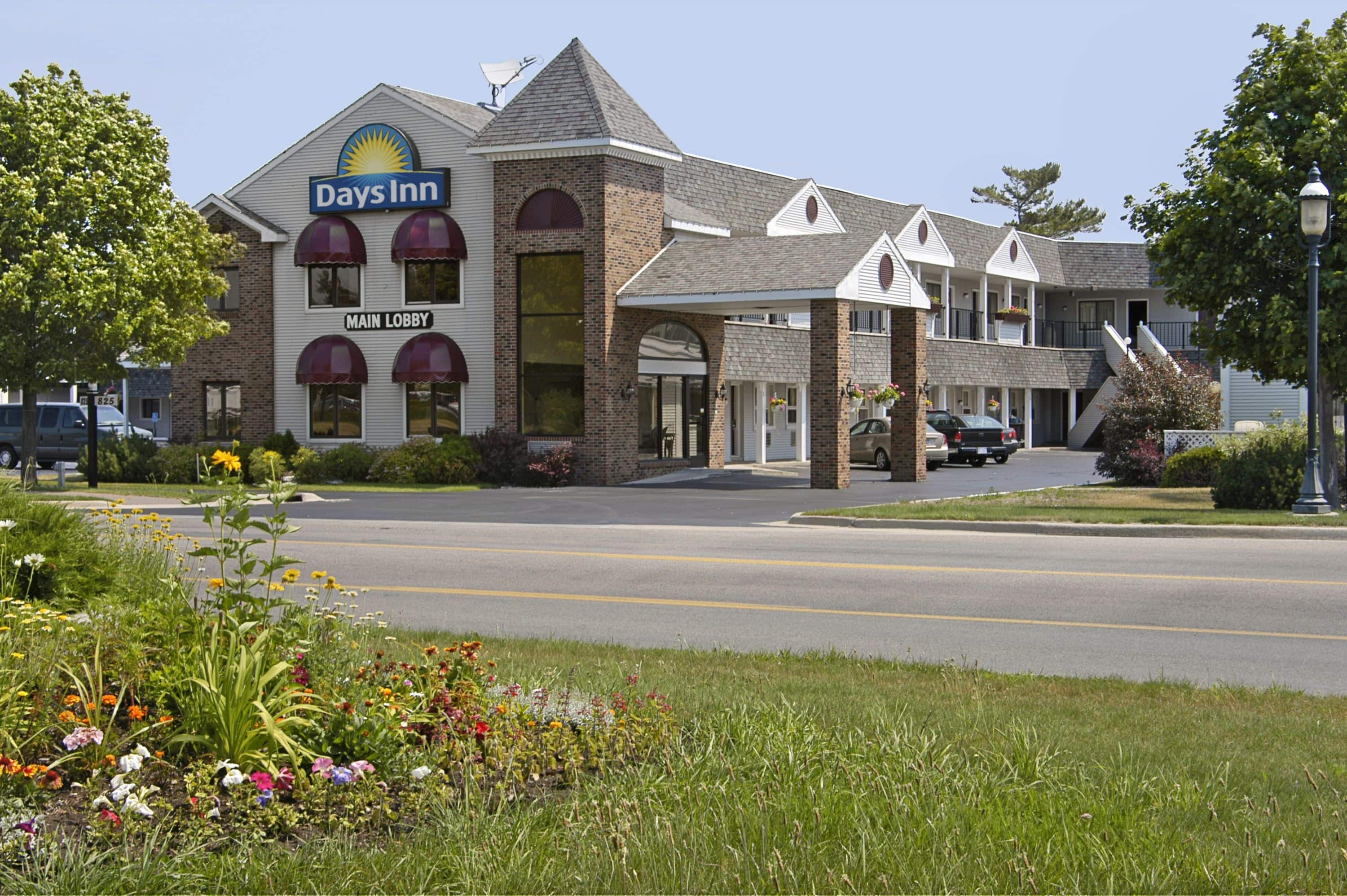 A Building With A Parking Lot And Flowers